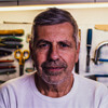 A man with grey hair and beard in front of some tools.